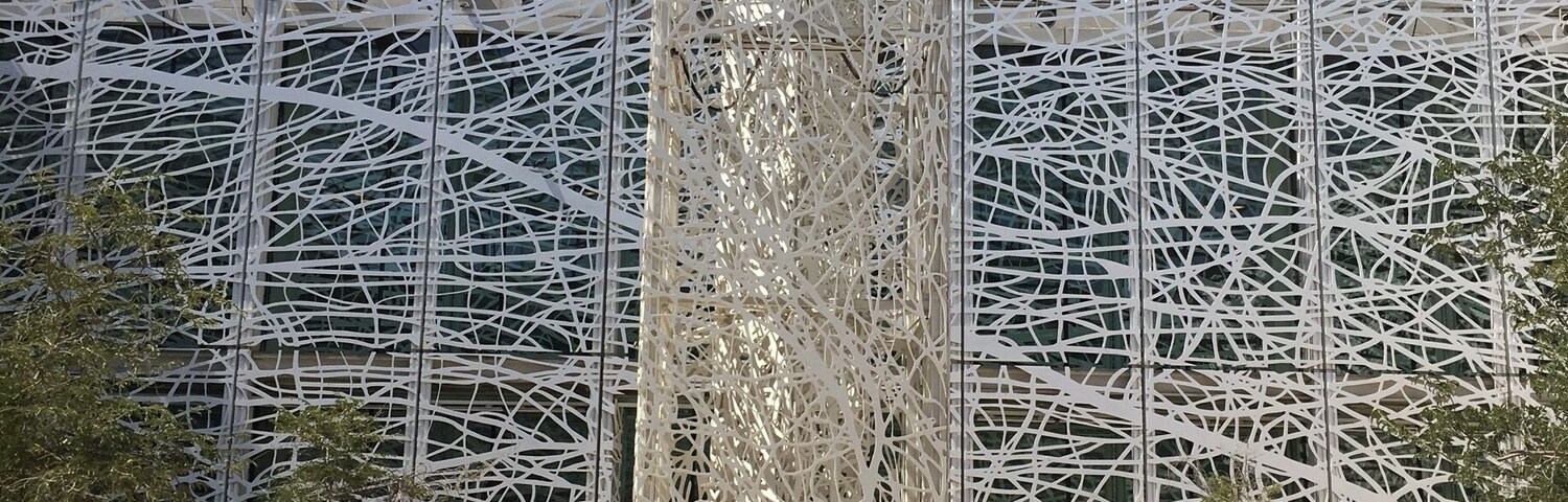 Um edifício moderno com fachada em estrutura complexa e uma estrutura vertical central.