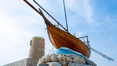 A wooden boat on a stone pedestal with a stone tower in the background.