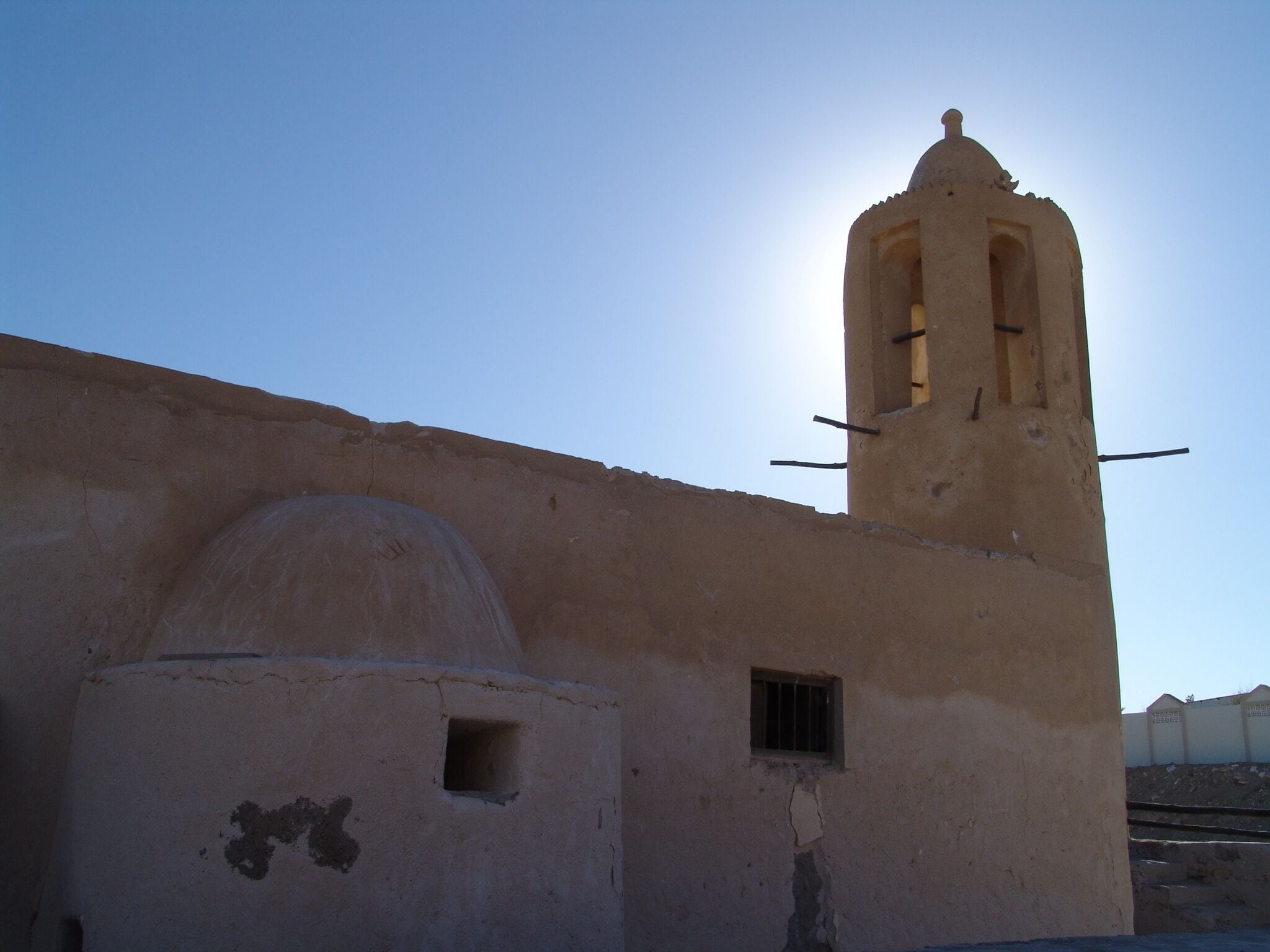 A weathered building with a bell tower, a small window, and a dome structure.