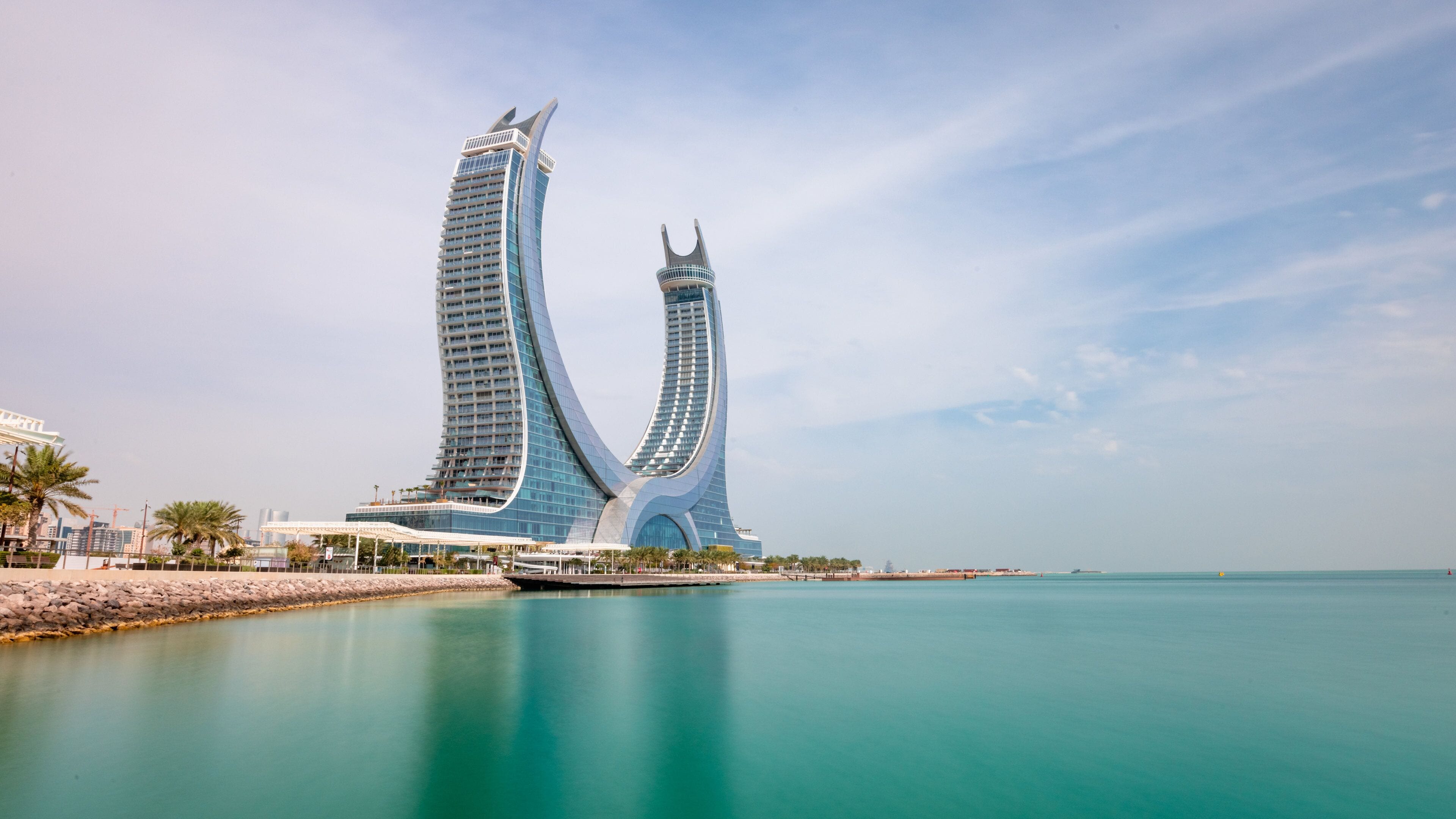 A modern architectural landmark with two curved towers by the waterfront.