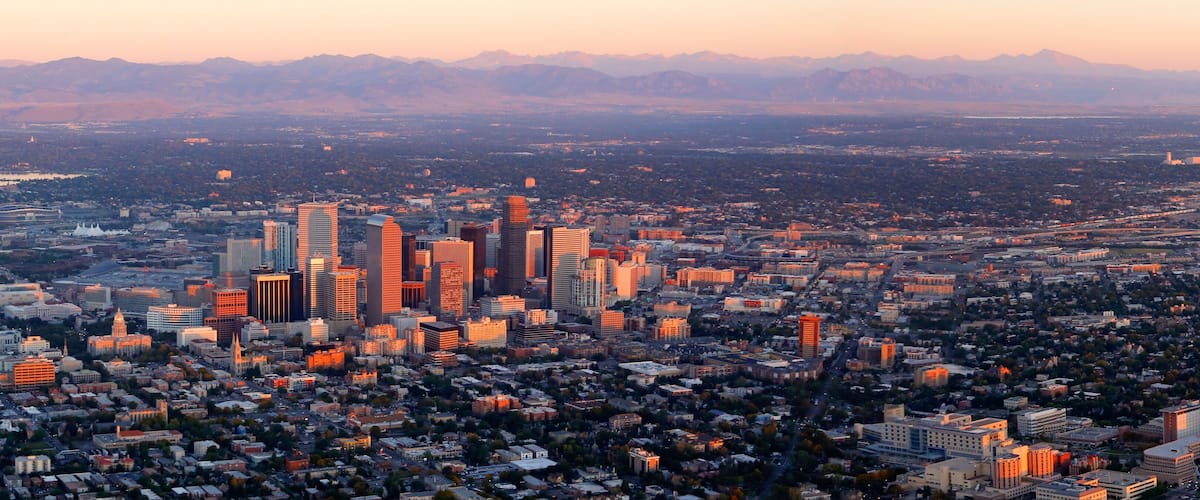 A cityscape with a prominent skyline of high-rise buildings, a dense urban area, and a mountainous backdrop.