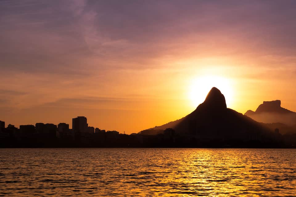 Un atardecer sobre un paisaje urbano con la silueta destacada de una montaña.