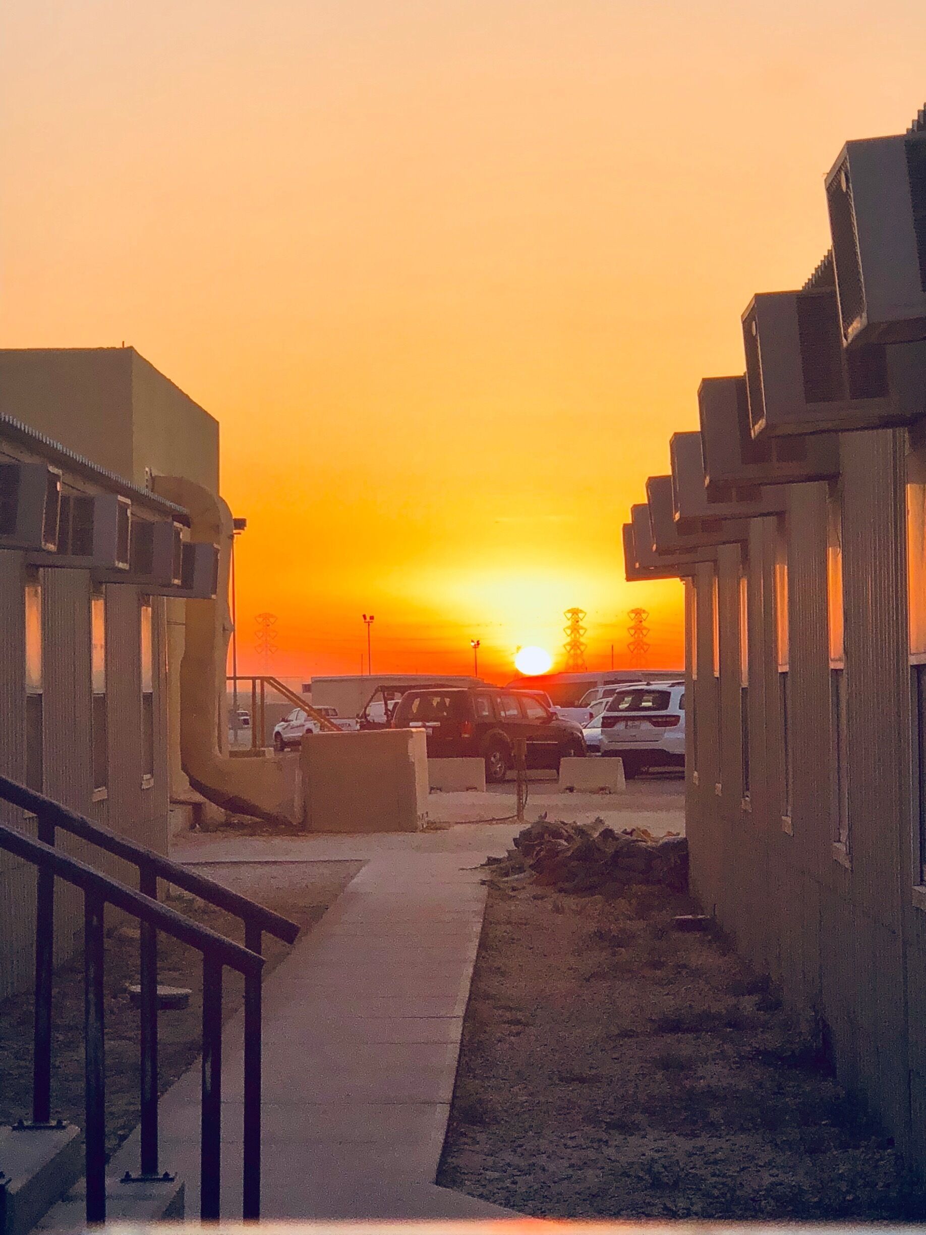 A sunset over a parking lot with buildings and a staircase.