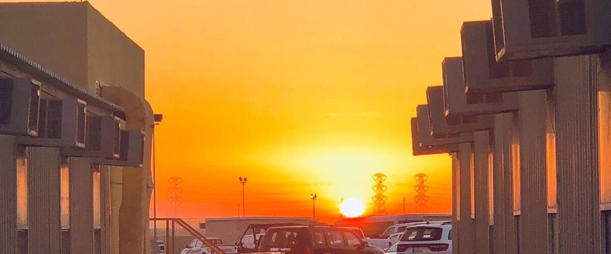 A sunset over a parking lot with buildings and a staircase.