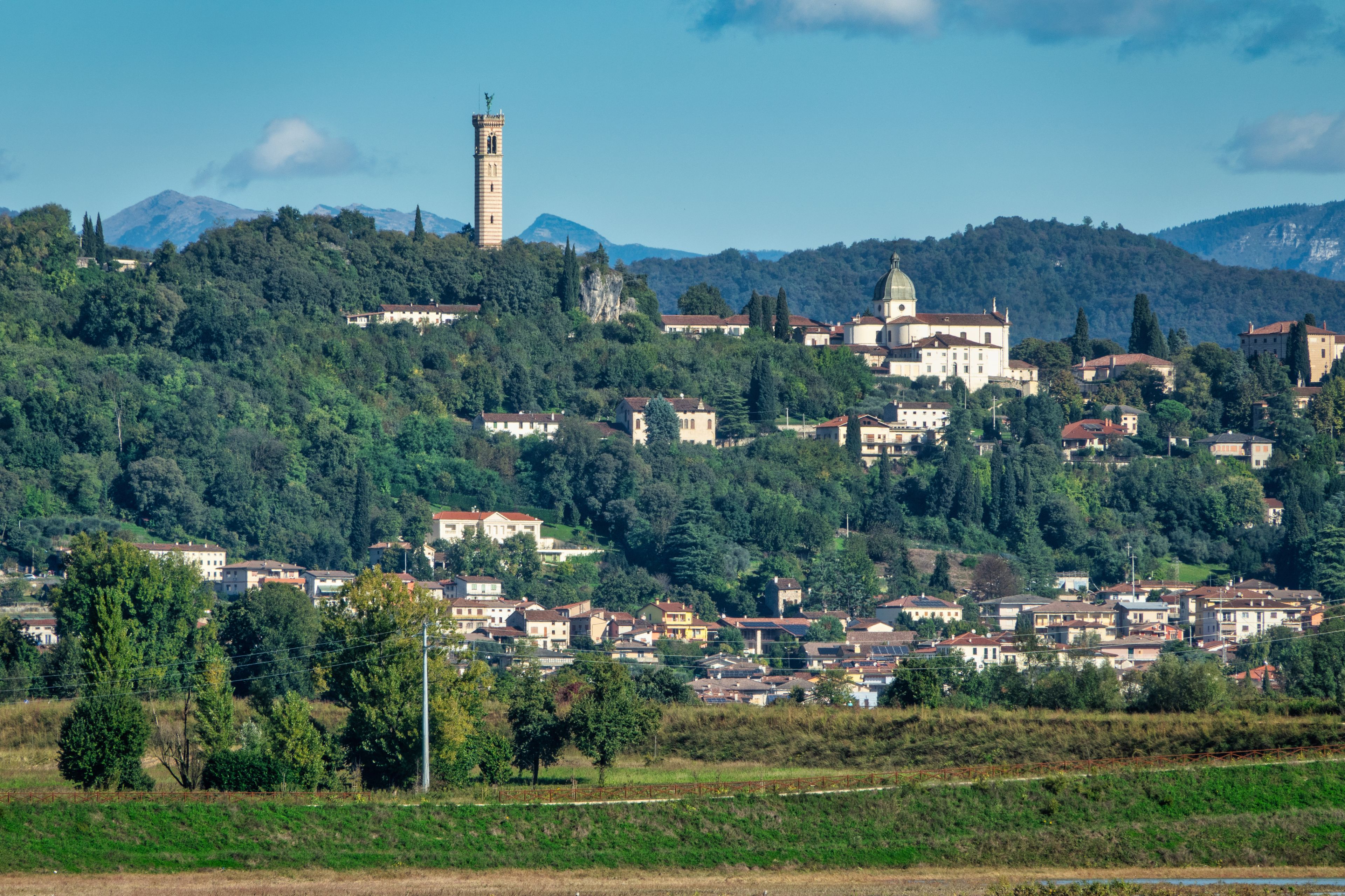 Une ville construite sur une colline, avec un imposant beffroi et une église surmontée d’un dôme.