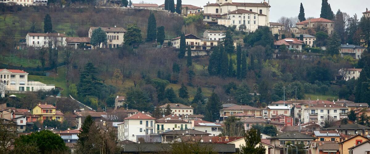 A town with a prominent tower, a church with a dome, and residential buildings on a hillside.