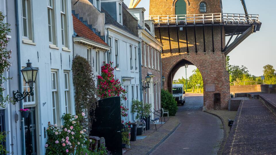 A street with a brick tower and white buildings with flower boxes.