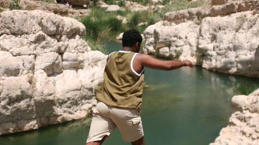 Wadi Shab is a truly magical place that is made even more amazing with a little local knowledge. To get there from Muscat, no 4WD required. Head along the road to Sur and not long after Fins Beach, take a turn off (slipway) to the right for Wadi Shab or Tiwi Village - it is signposted. Head down under the road and turn left to go underneath the highway. When you come out from under the bridge, do not turn immediately right, cross this road and turn right immediately after it. Follow this road through the village and down the steep hill to the causeway. When you cross over the causeway, turn right and park under the highway.
Once you have reached here, you need to take a boat across to the other bank in order to walk up the Wadi. It costs 300 baisa (about 80 US cents). Try to have small change for this - you would be lucky if these guys carried change for a 10, let alone anything bigger. Check what time the last boat goes back - it changes with the season.
Once you are across, there is a long but rewarding walk ahead. Luckily there are lots of stunning pools to take a dip in along the way. In 2012, Red Bull held the finals of the Cliff Diving Championships here. Eventually, the walk kind of stops at the water's edge. There is just a rock wall in front of you and a beach of smooth rock to enter the wadi. This is where it is time to get wet. You will need a waterproof bag if you are carrying valuables and I strongly recommend water shoes of some kind.
Keep following the wadi upstream. There will be some climbing over rocks and up small gravelly waterfalls and some swimming. How much will depend on the current water level.
You will reach a rock wall in front of you and the wadi just seems to appear out of it. There are now only 2 ways to go - back where you came from - or through the wall. There is a crack in the middle of the wall. Go to where this "meets" the water. If the water level is high, it will be all the way up and the only way through is to swim under rock. This is without a doubt dangerous going in blind and one of my least favourite things. I won't do this. If the water level is low enough, which it always has been for me, you can "swim" under, with enough room to get your head through, so you can both see and breathe - a much safer option. You can use your hands on the rock to propel you through.
What do you do all of this for...? You are now in a cave with a waterfall. It is partially open at the top, so it is shady rather than dark and the locals have fixed a rope up through the waterfall so you can climb up and jump in. With so many other options further down river for jumping in or stopping in the shade by the water, this may seem like a lot, but it is truly beautiful.
Note: Take plenty of drinking water, sunscreen, hat and energy food. It is warm even in winter - especially if you are from colder climes.
But most of all - enjoy! And don't be surprised if there are some local lads around eager to show you the way!