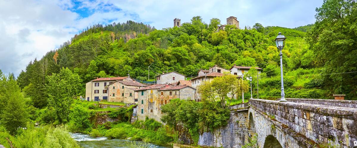 A river flowing through a village with stone buildings and a bridge.