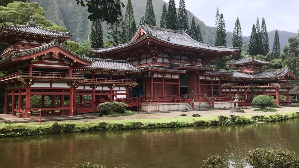 Een traditioneel Japans tempelcomplex met meerdere gebouwen, een vijver en omliggend groen.
