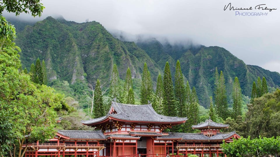 A traditional Japanese temple surrounded by lush greenery and mountains.