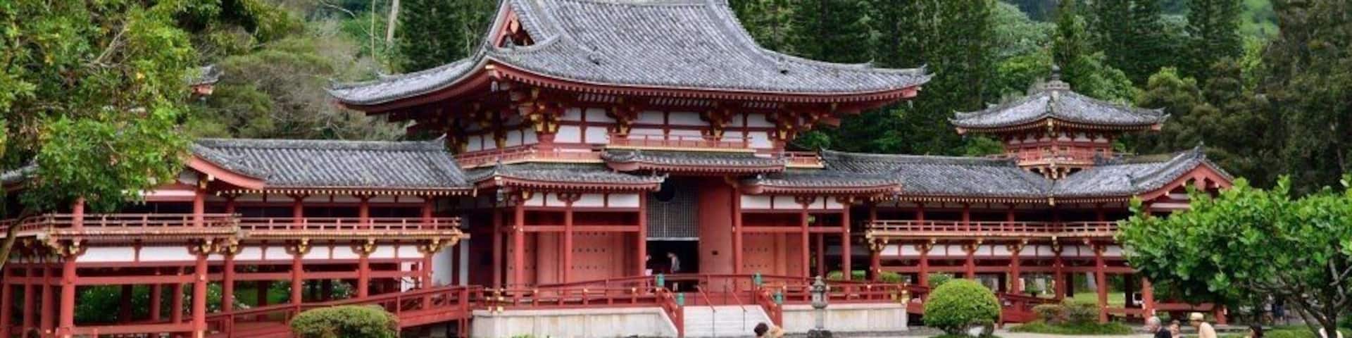 A traditional Japanese temple with red wooden structures and a mountainous backdrop.