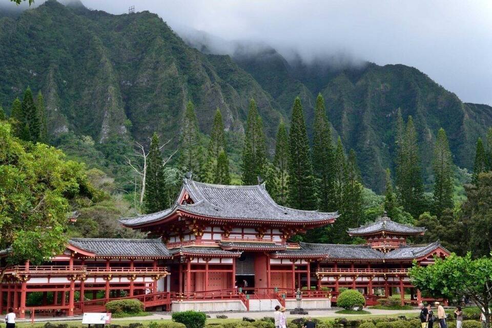 A traditional Japanese temple with red wooden structures and a mountainous backdrop.