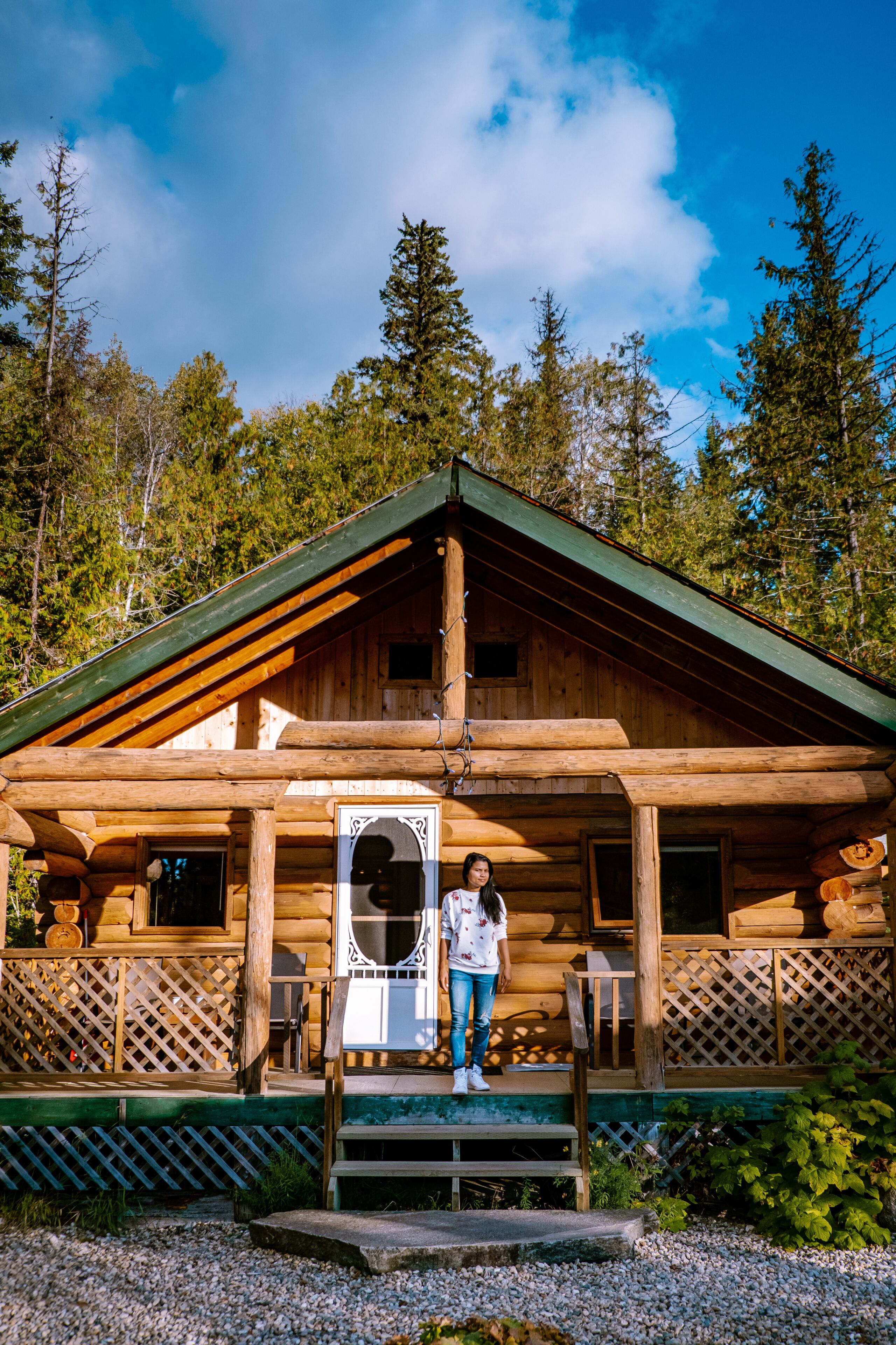 young girl in front of wooden cabin, cottage in the forest of Canada British Colombia