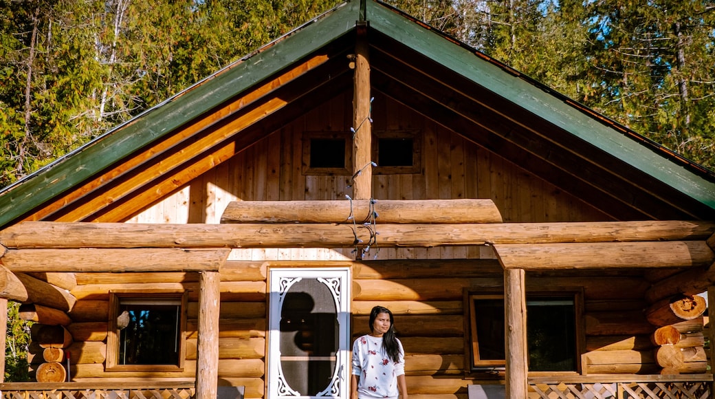 young girl in front of wooden cabin, cottage in the forest of Canada British Colombia