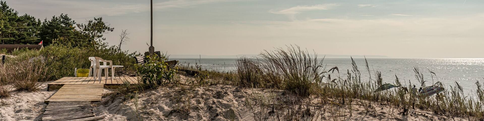 Bluewater Beach, Tiny Township, Ontario, Canada - August 10, 2014: A boardwalk across the dunes leads to a platform with seating and a flag overlooking Georgian Bay on a sunny summer morning