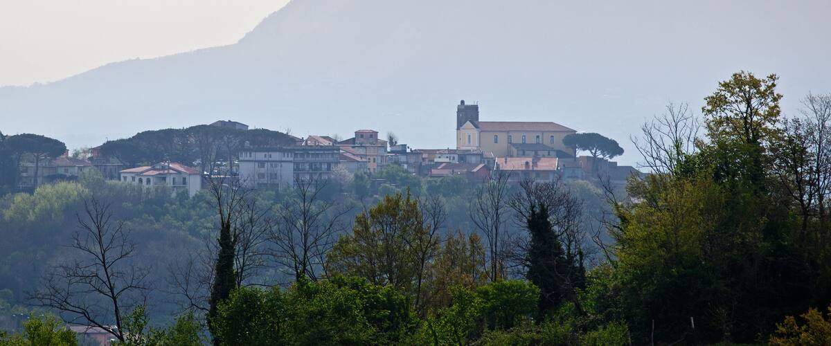A coastal town with buildings and a prominent mountain in the background.