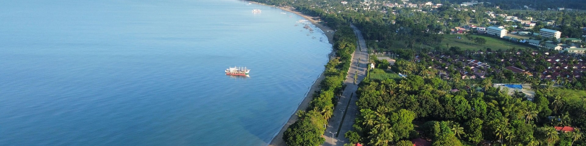 Aerial drone shot of the Bayawan City boulevard and blue ocean, the Philippines