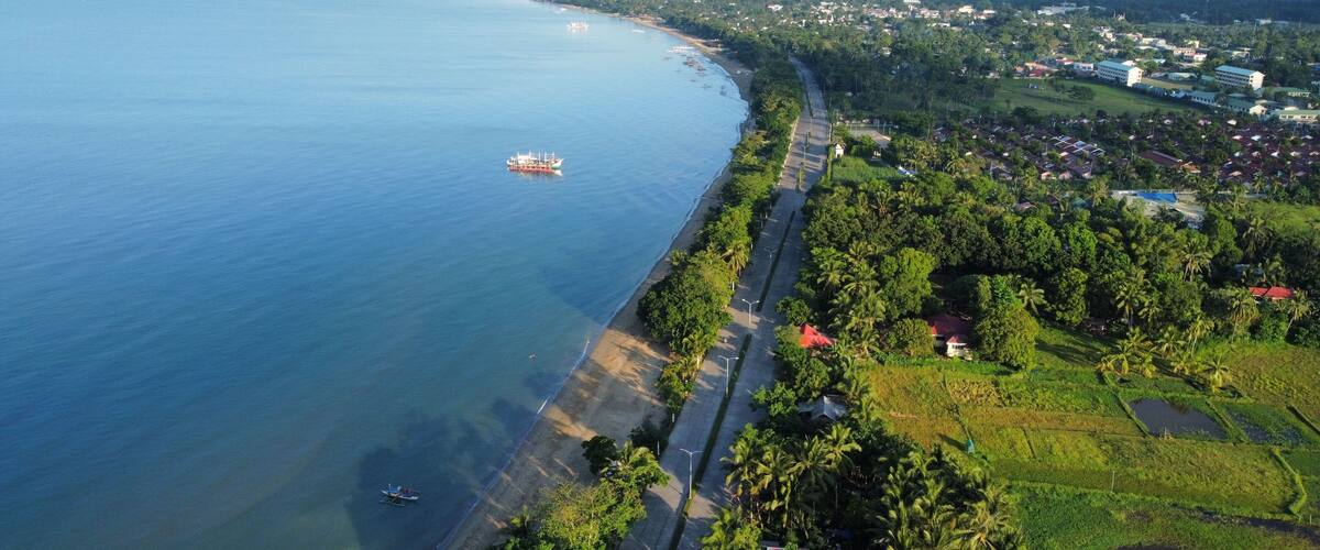 A coastal town with a beach, a road, and a large body of water.