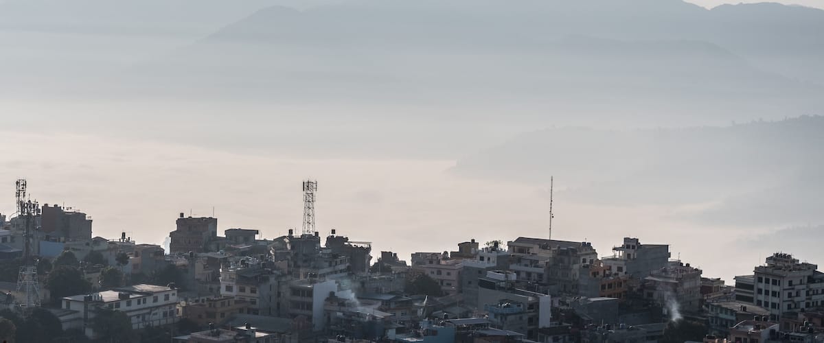 A cityscape with buildings and a mountain range in the background.