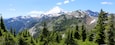 A snow-capped mountain range with dense forests in the foreground.