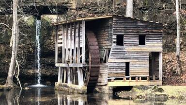 A rustic wooden structure with a waterfall in the background.