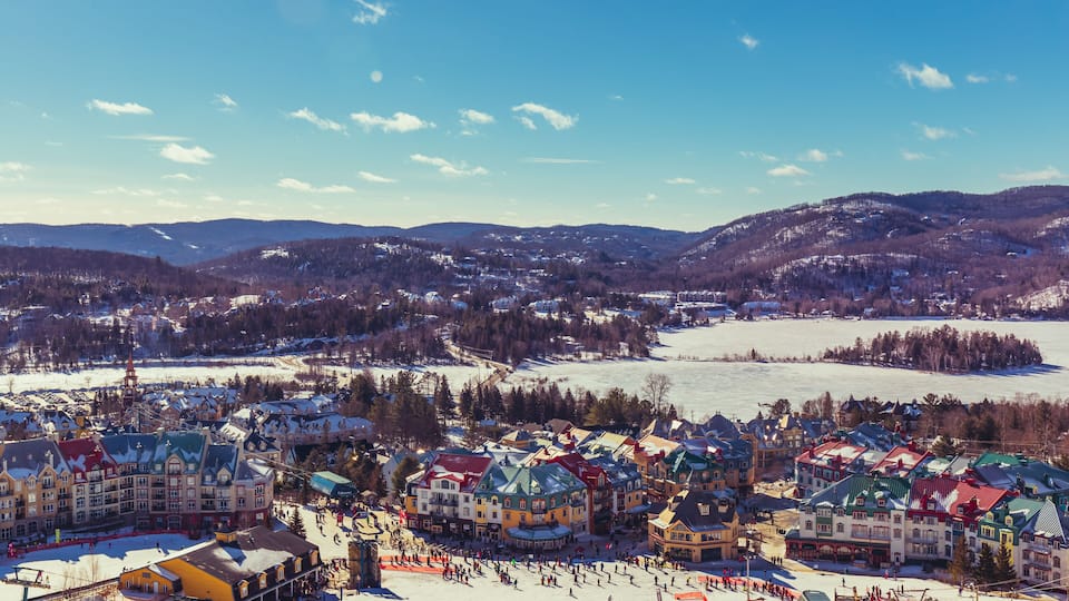 A snow-covered village with colorful buildings and a ski slope.