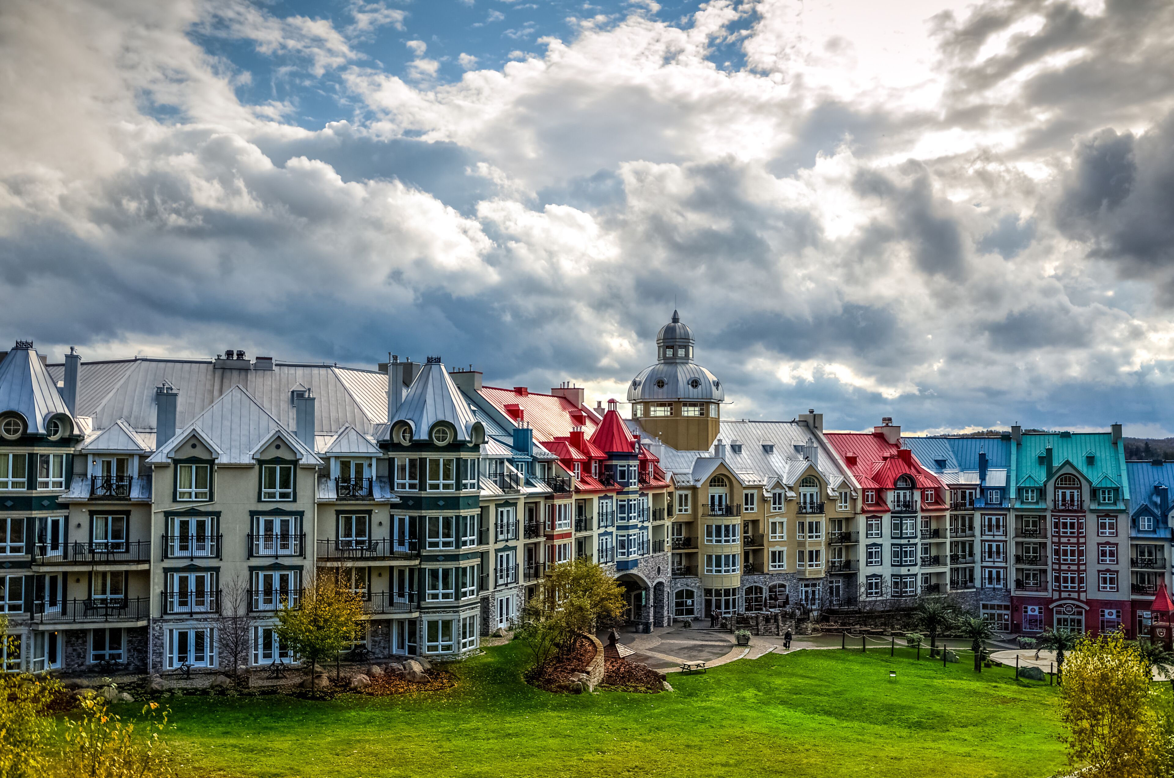 Colorful buildings with a prominent tower and a green park in the foreground.