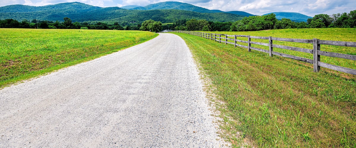 Farm road fence in Roseland, Virginia near Blue Ridge parkway mountains in summer with idyllic rural landscape countryside in Nelson County
