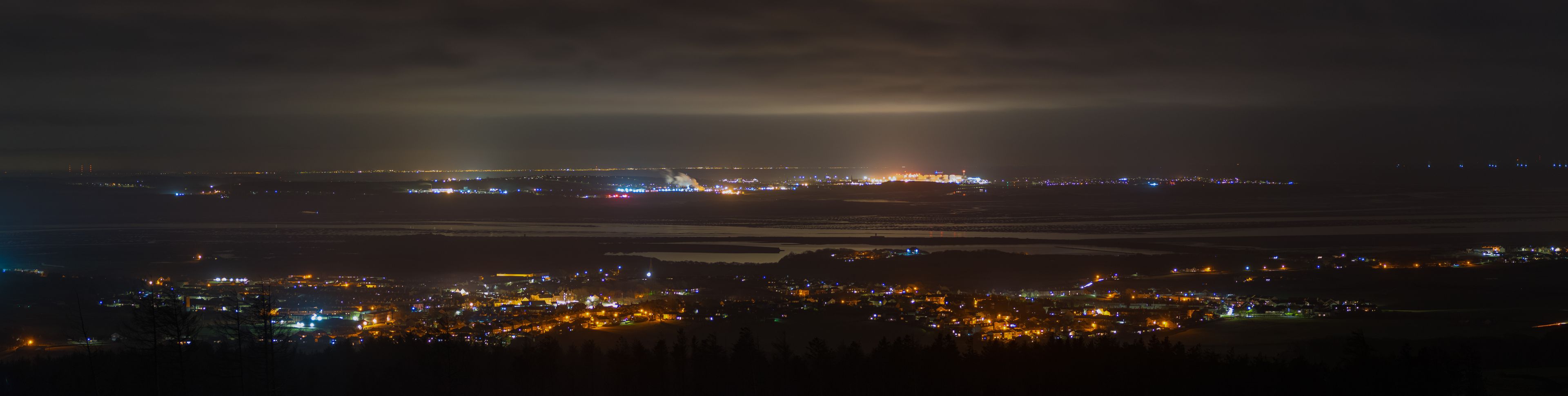 A nighttime cityscape with a prominent airport and a densely lit residential area.