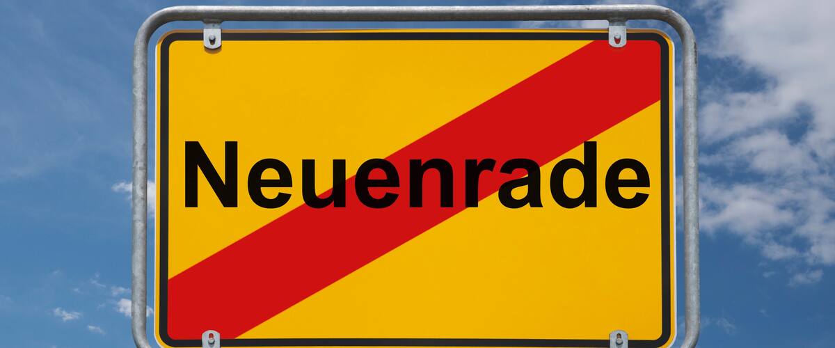 A road sign with the word "Neuenrade" against a blue sky with clouds.