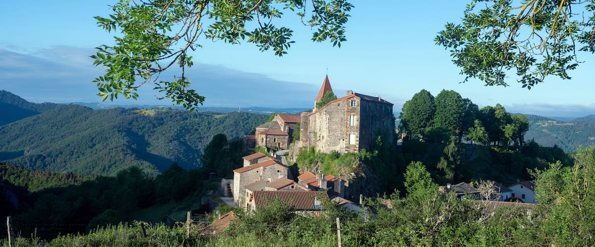 A historic stone castle surrounded by lush green hills and trees.