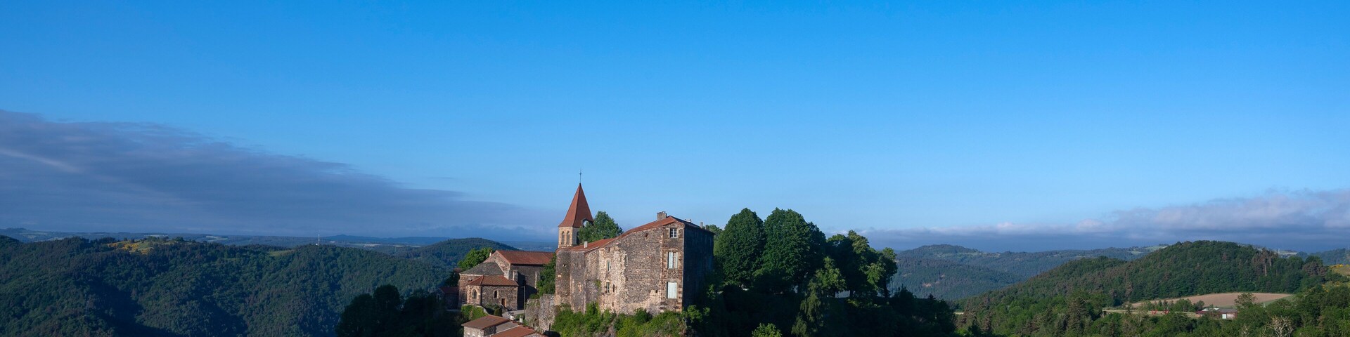 Un pueblo histórico con edificios de piedra y una iglesia en una ladera.