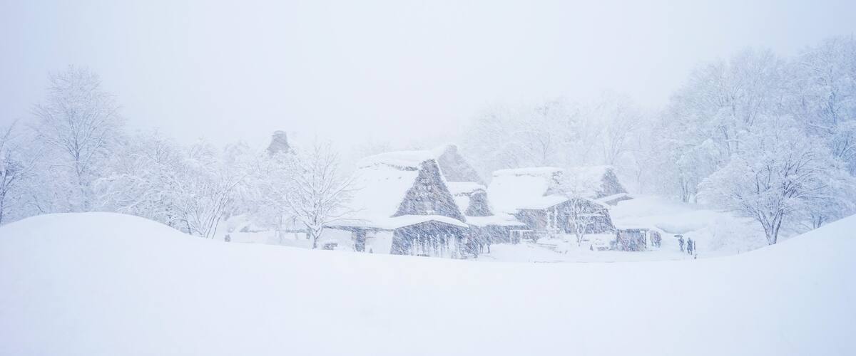 A snow-covered village with traditional houses and trees.