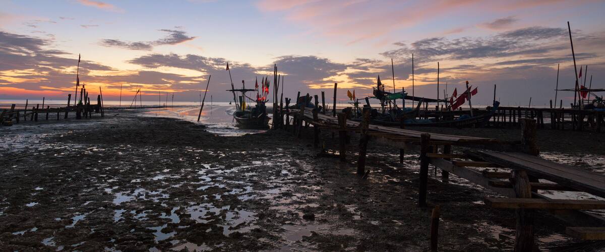 A sunset over a beach with boats docked on wooden piers.