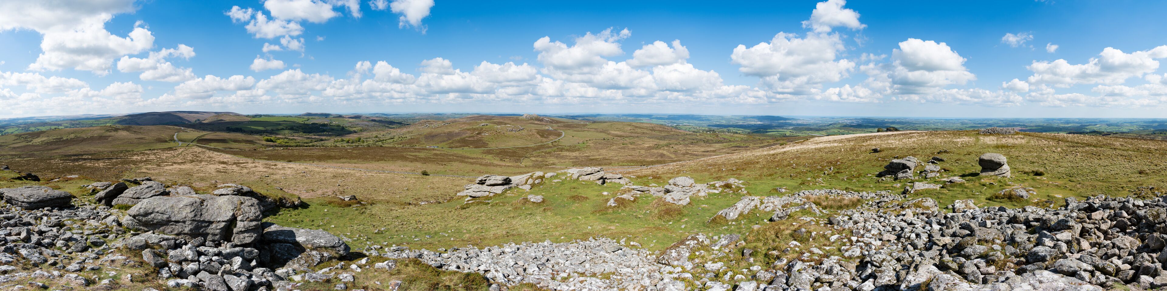 A mountainous landscape with rocky outcrops and rolling hills under a clear blue sky.