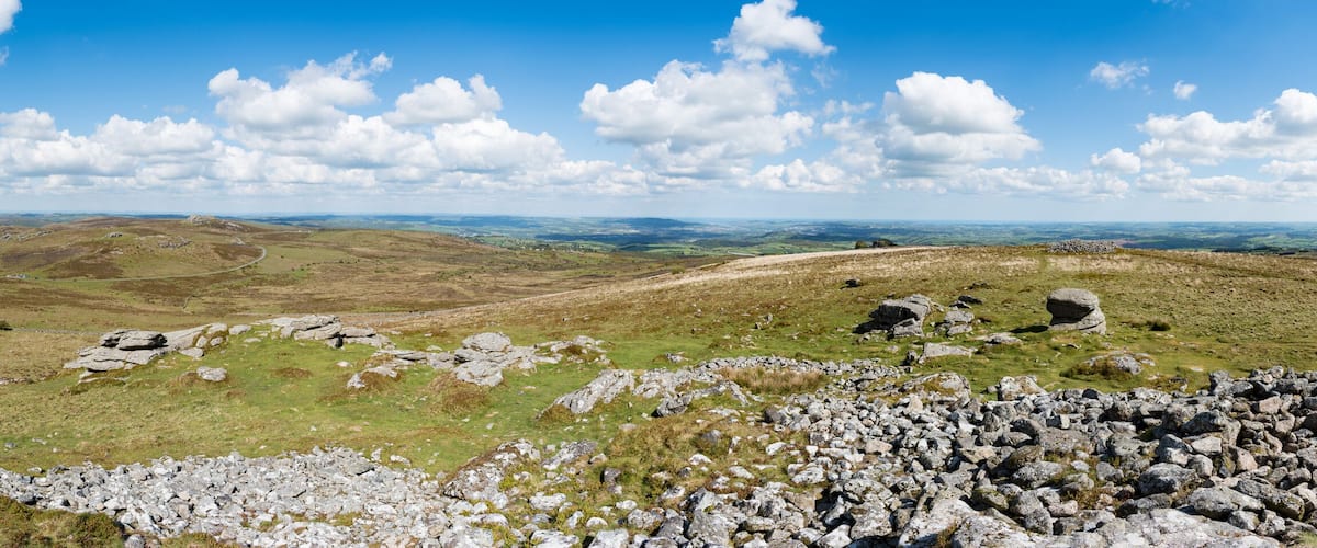 A mountainous landscape with rocky outcrops and rolling hills under a clear blue sky.