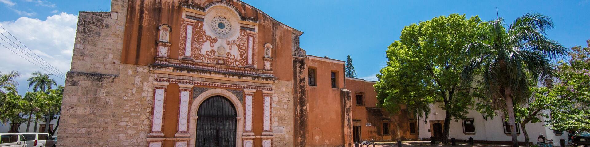 A historic building with a circular plaza, palm trees, and a clear blue sky.