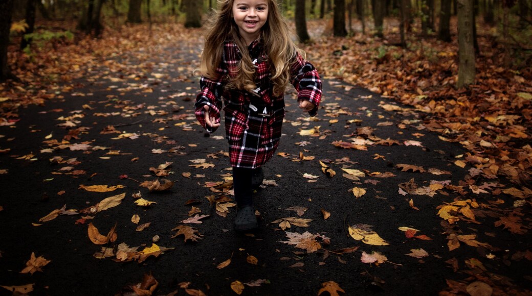 Happy young girl running down path with colorful leaves and trees