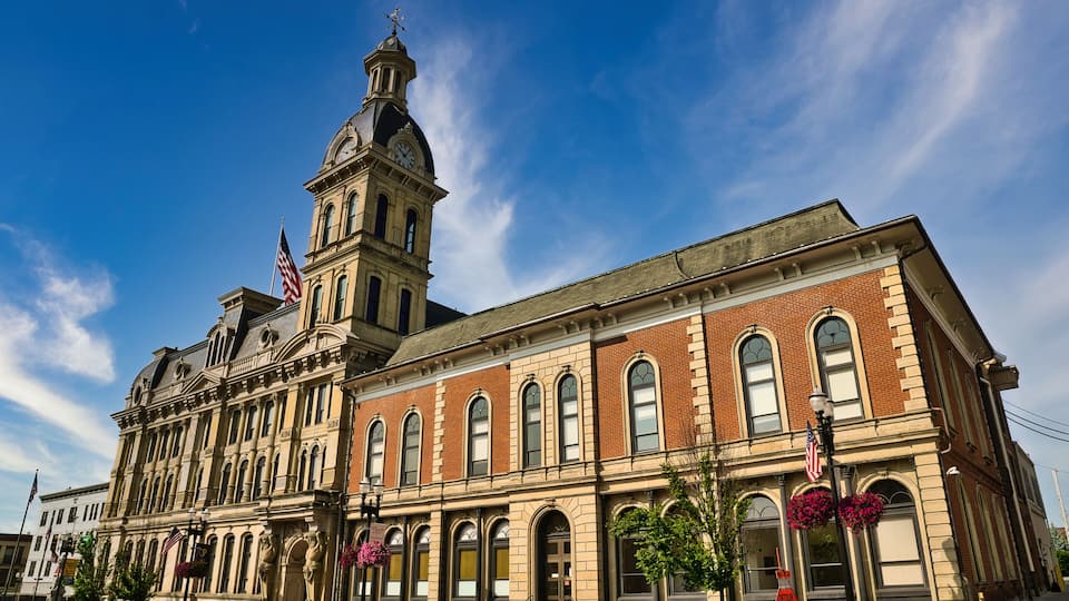 A historic building with a clock tower, American flags, and a red stop sign.