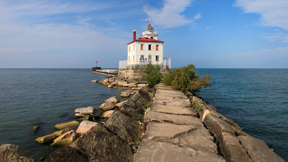 A lighthouse on a rocky outcrop with a clear sky.