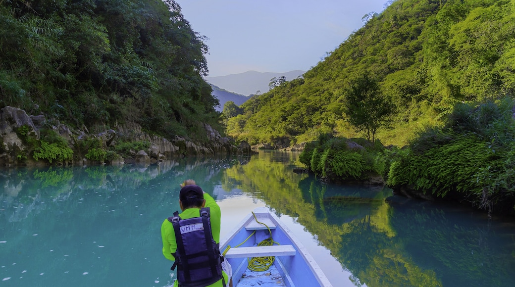 TAMUL, SAN LUIS POTOSI MEXICO - January 6, 2020: Rear view of man in raincoat and vest rowing in canoe. Active, adventure, outdoors, in tamul river