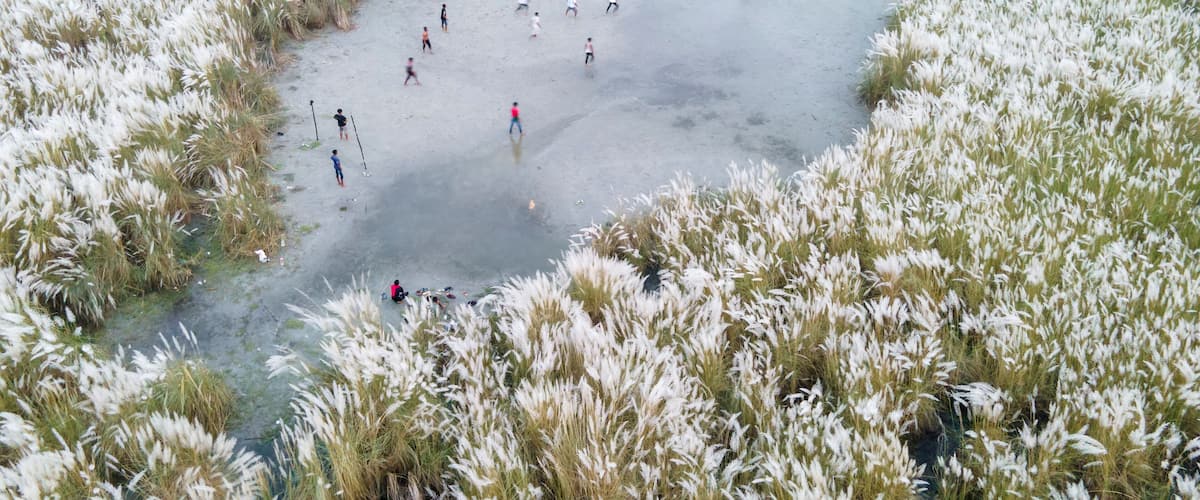 Aerial view of boys playing soccer on a permanent sand field surrounded by temporary flower beds in the capital city Dhaka, Bangladesh.