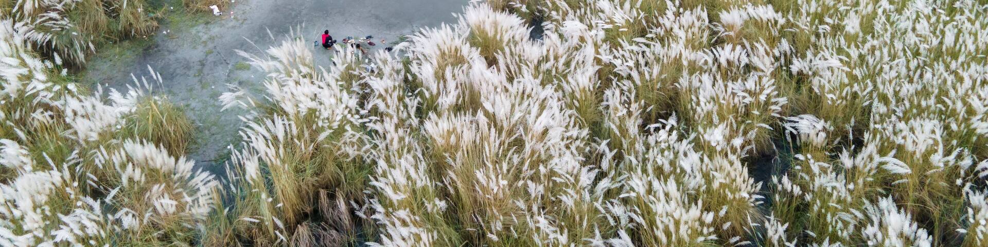 Aerial view of boys playing soccer on a permanent sand field surrounded by temporary flower beds in the capital city Dhaka, Bangladesh.