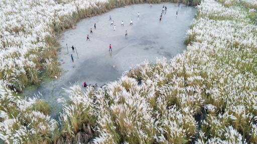 Aerial view of boys playing soccer on a permanent sand field surrounded by temporary flower beds in the capital city Dhaka, Bangladesh.