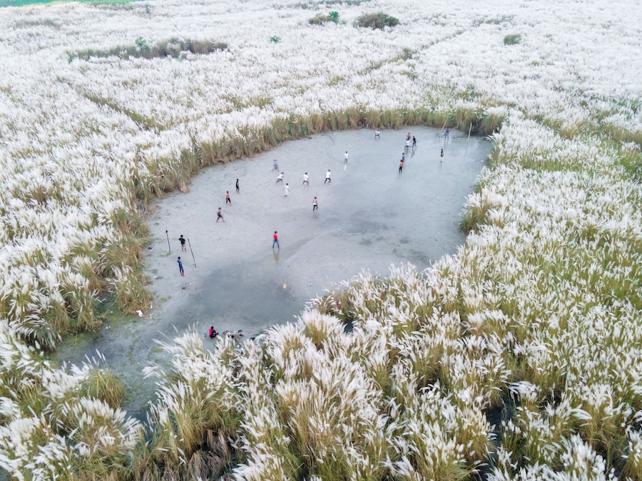 Aerial view of boys playing soccer on a permanent sand field surrounded by temporary flower beds in the capital city Dhaka, Bangladesh.