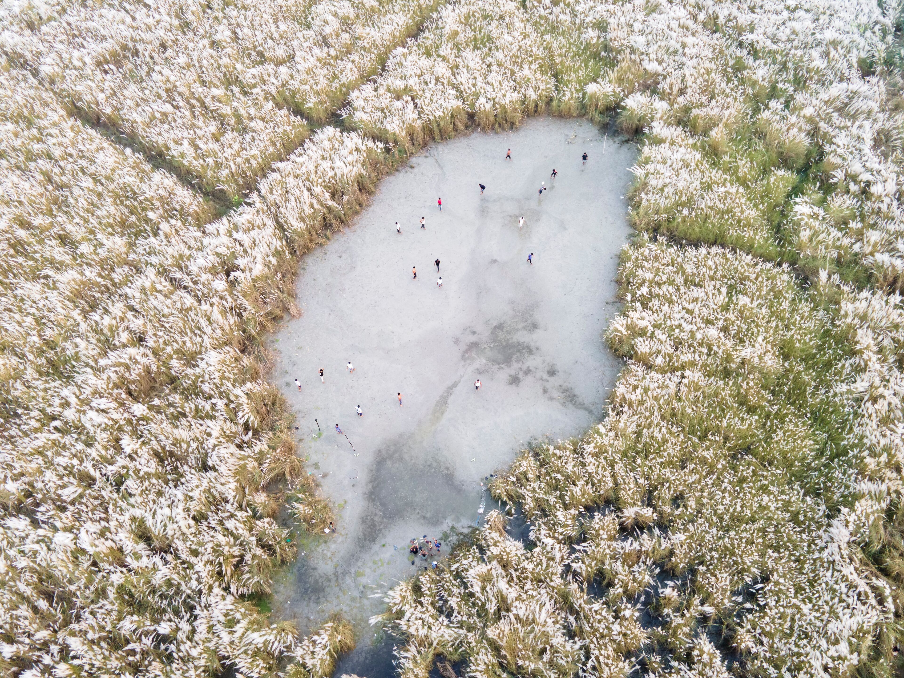  Aerial view of boys playing soccer on a permanent sand field surrounded by temporary flower beds in the capital city Dhaka, Bangladesh.