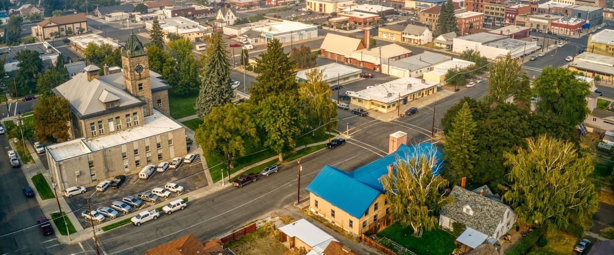 An aerial view of a town with a prominent church, a blue-roofed building, and a mix of commercial and residential structures.
