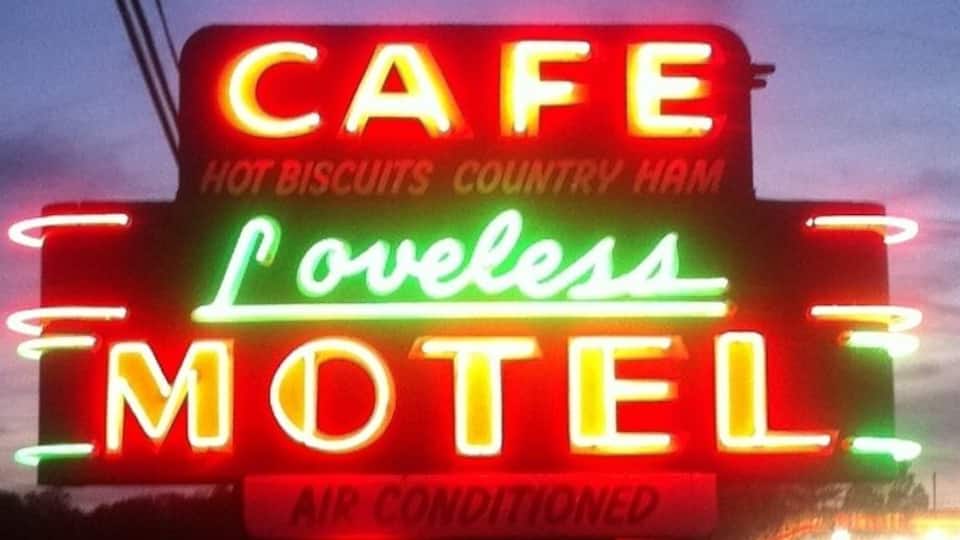 A neon sign for a cafe and motel with the words "Cafe," "Loveless Motel," and "Air Conditioned."