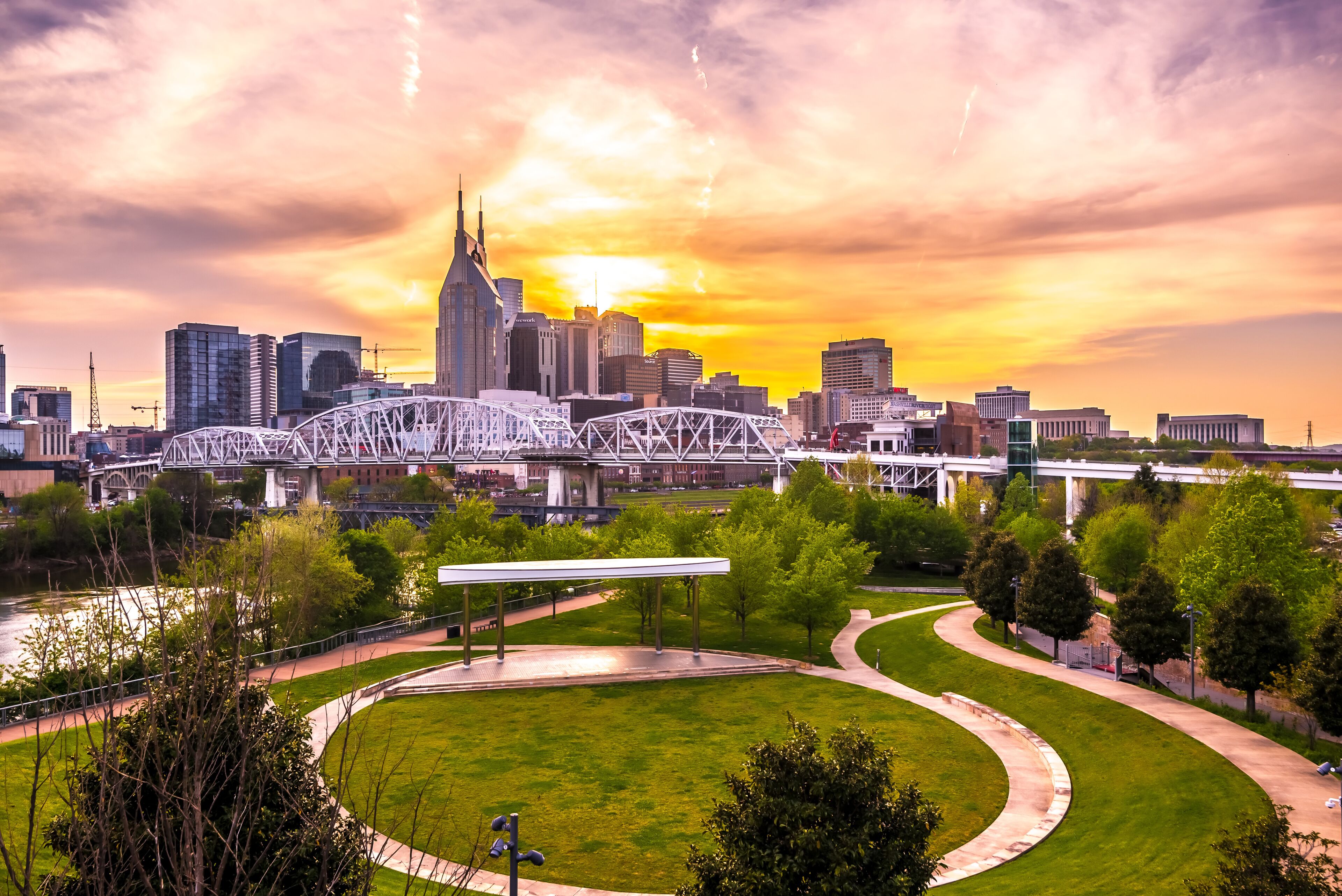 A city skyline with a prominent bridge and a park with a curved pathway.